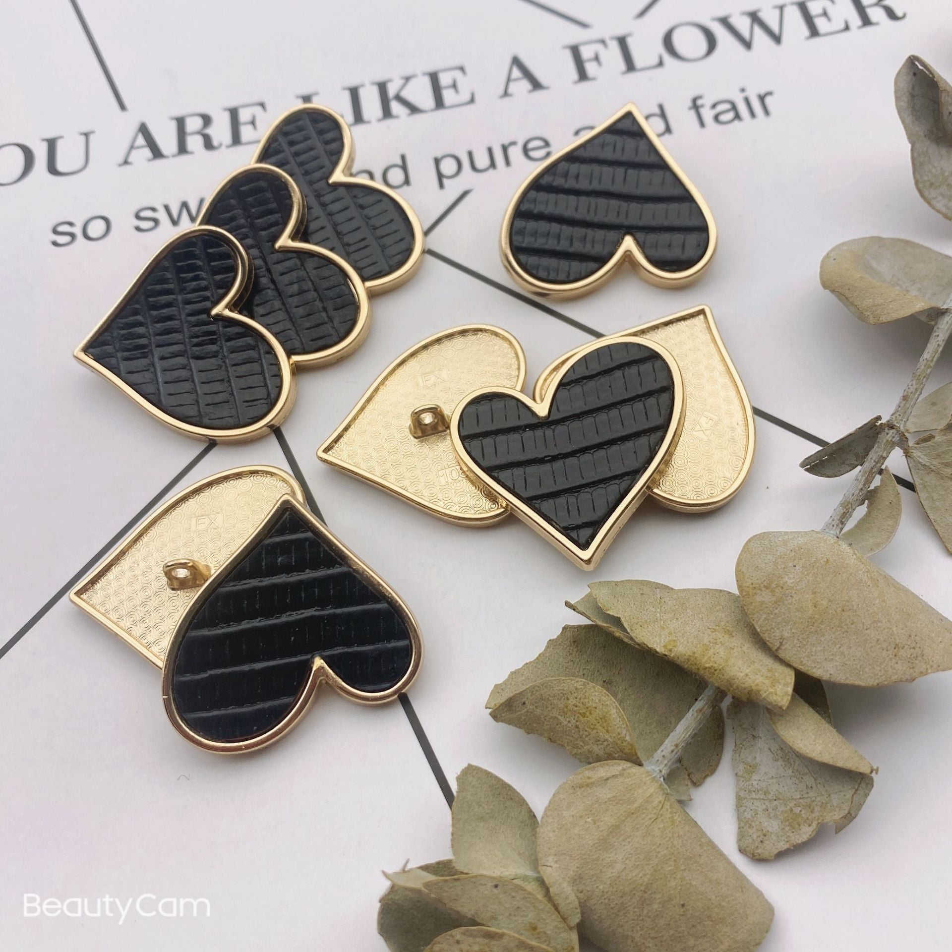Heart-shaped buttons in black and cream, gold-tone metal edges and shanks, 25mm