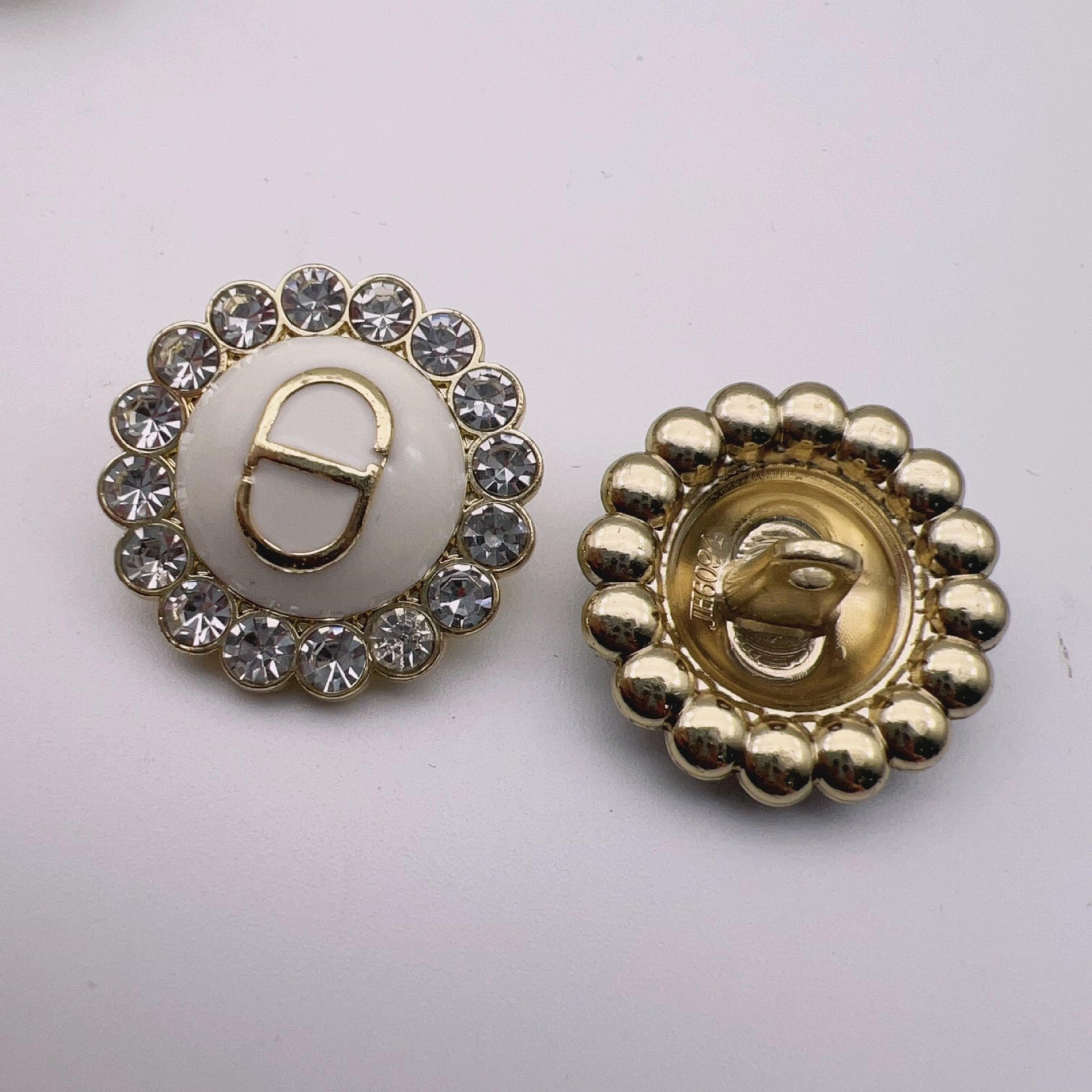 Round metal shank button: white enamel center with crystal rim and gold-tone beaded back