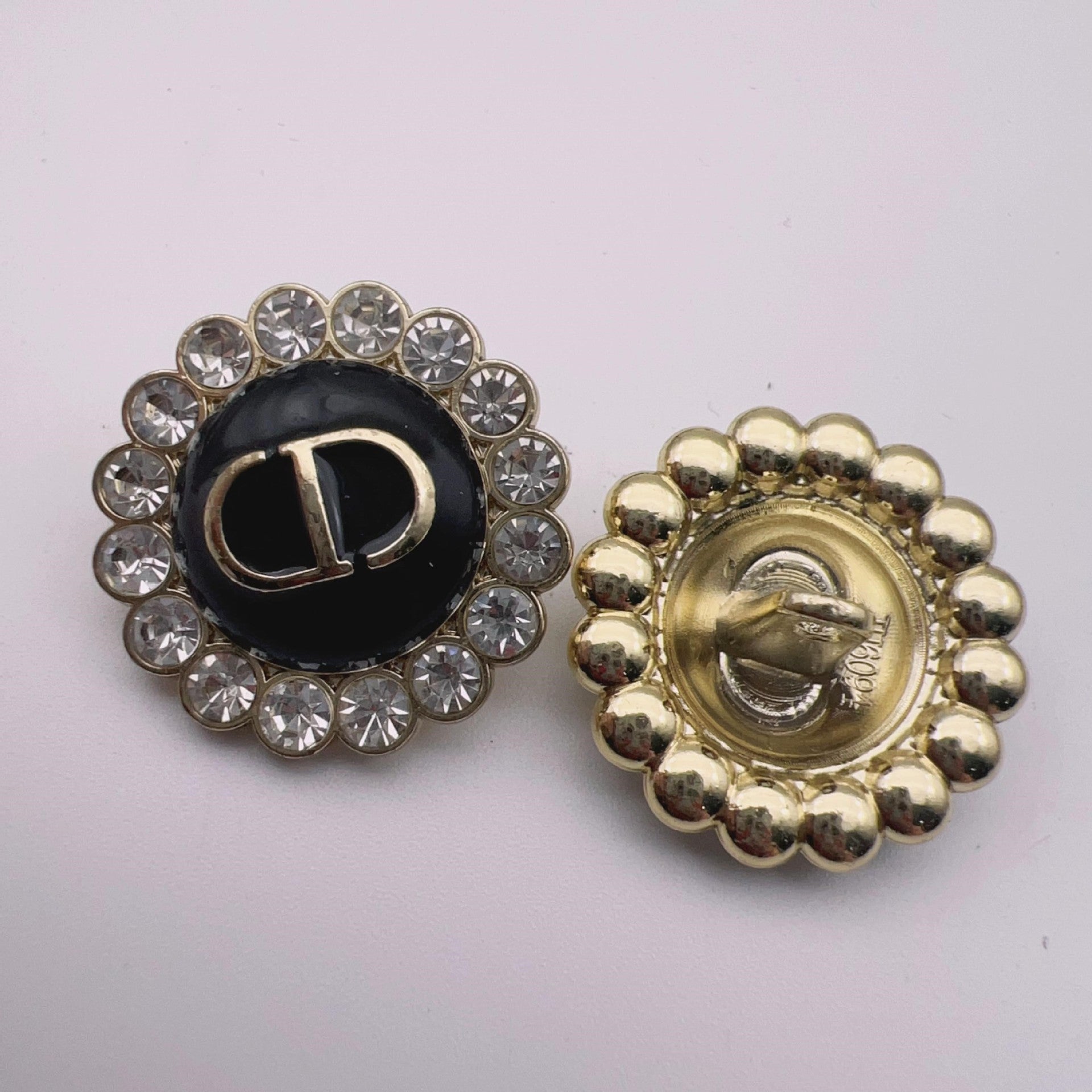 Round metal shank button: black enamel center with crystal halo and gold-tone beaded back
