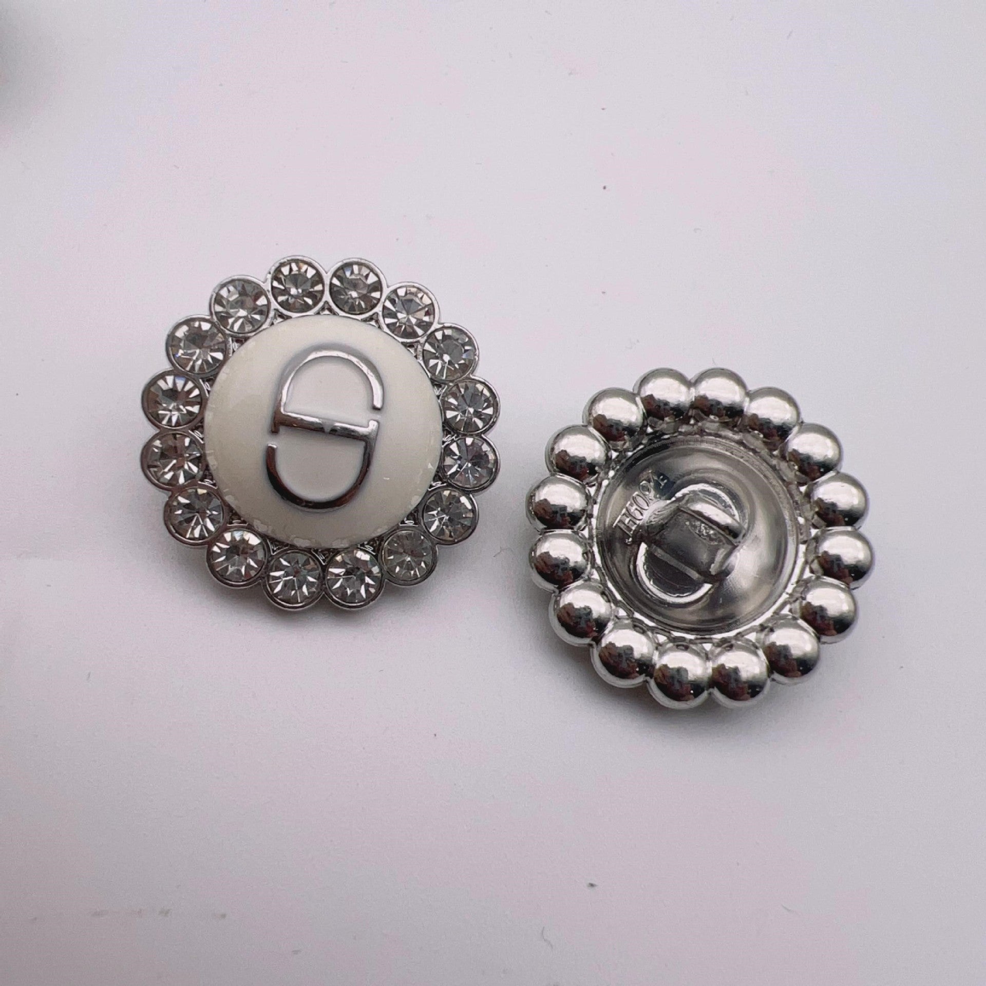 Round metal shank button: white enamel center with crystal halo and silver-tone beaded back