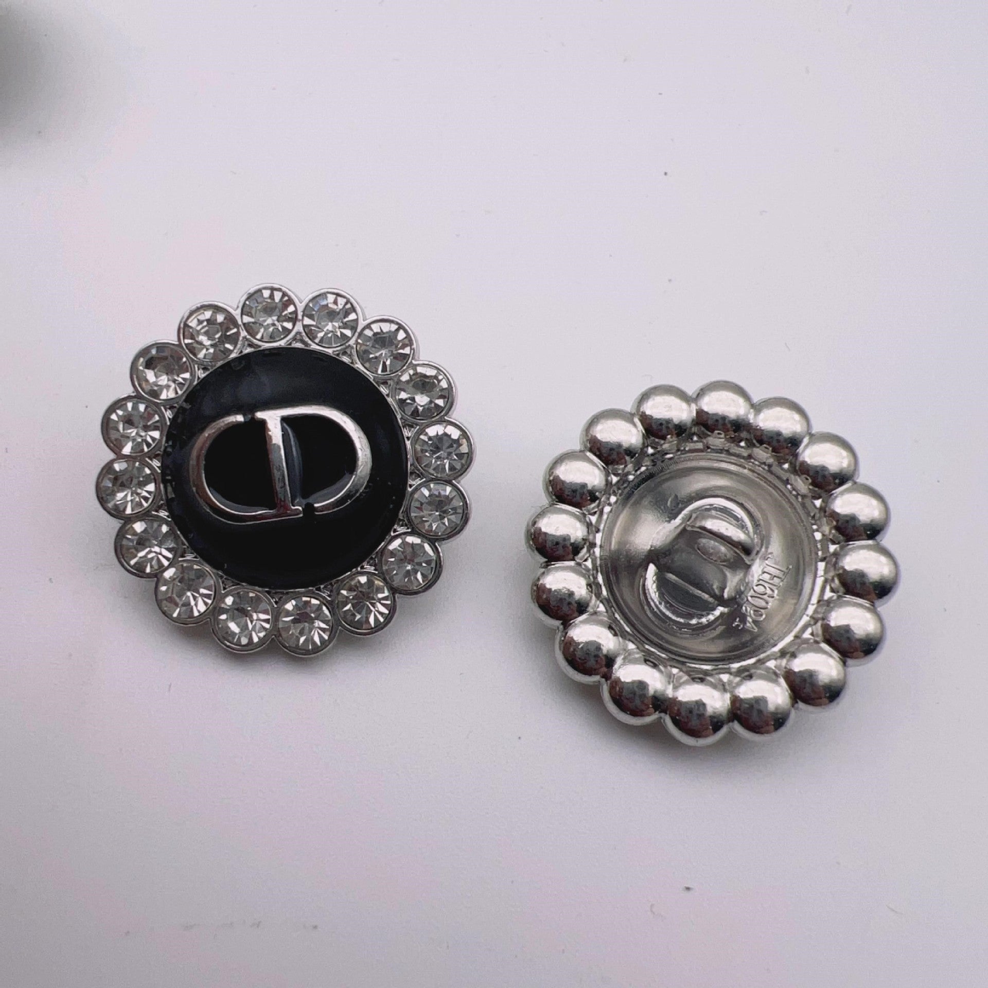 Round metal shank button: black enamel center with crystal halo and silver-tone beaded back