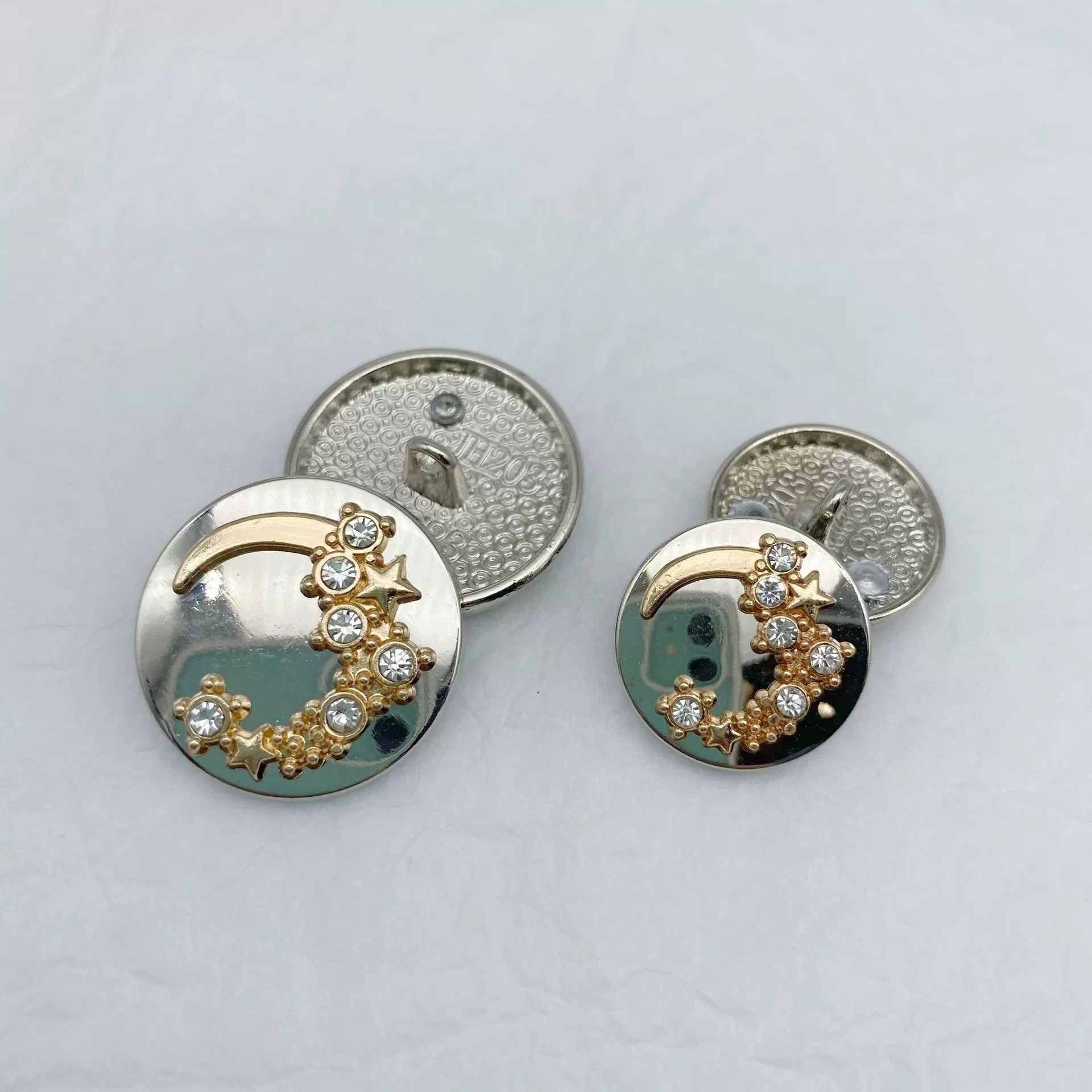 Runde Knöpfe mit Mondbogen und Sternen; klare Strasssteine, Vorderseite silbern und gold