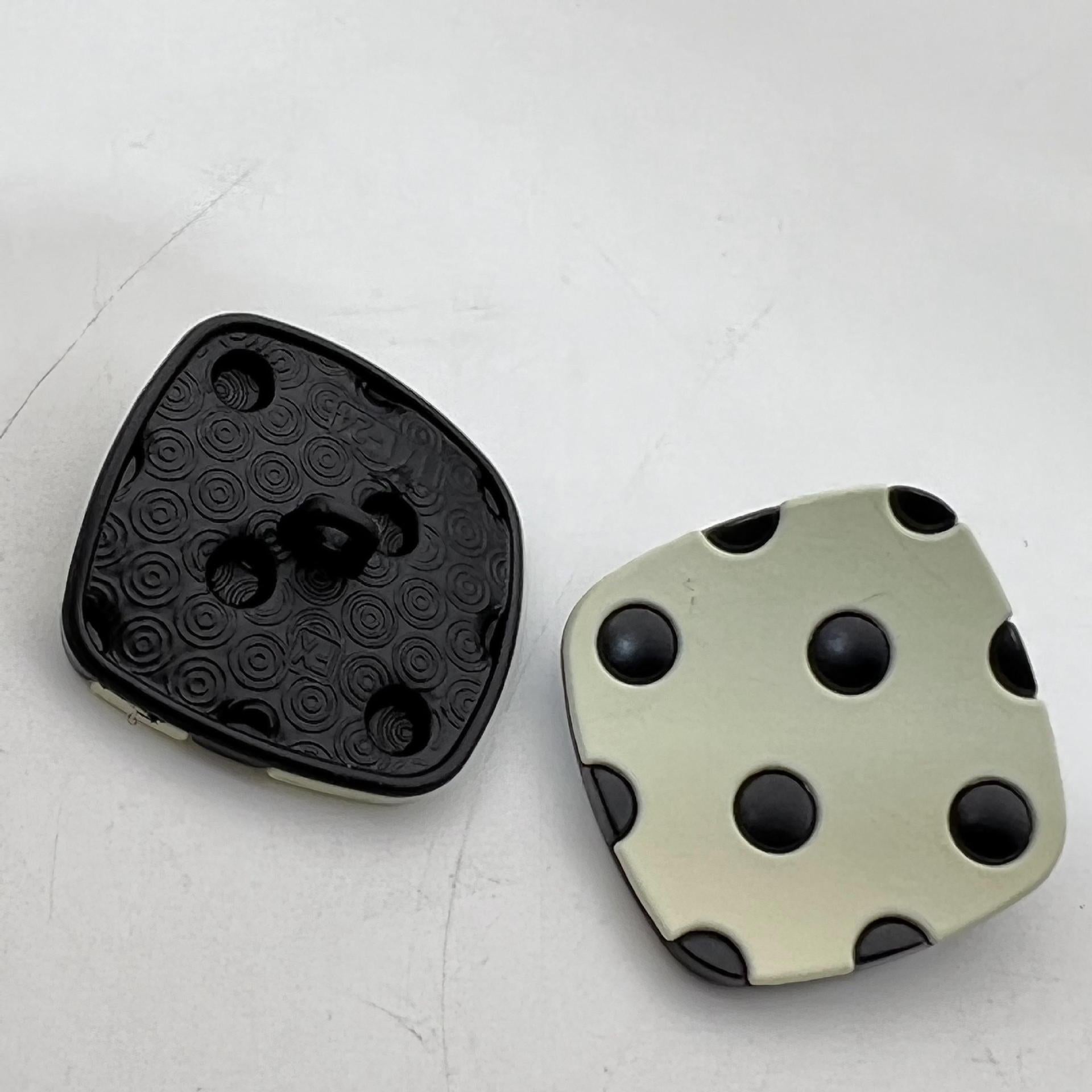 Curved square metal shank buttons with four studs; matte black and pale green tones