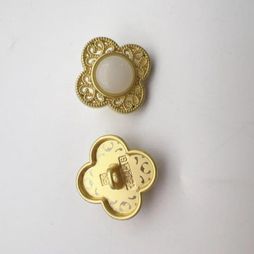 Gold-tone hollow flower shank button, off-white center with ornate filigree edges