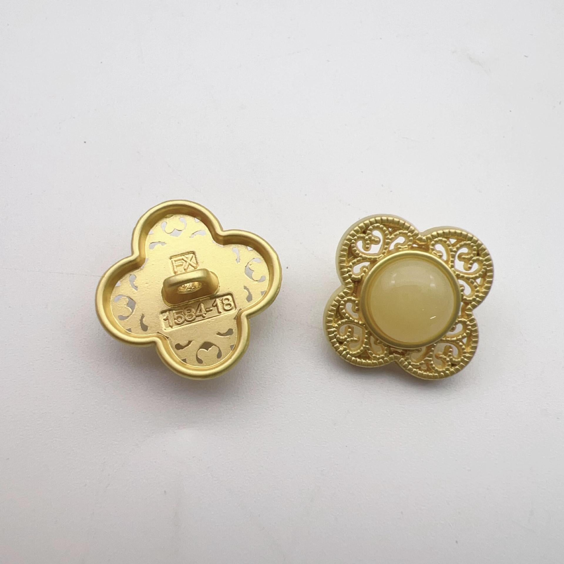 Gold-tone hollow flower shank button, light yellow-beige center; decorative back stamp