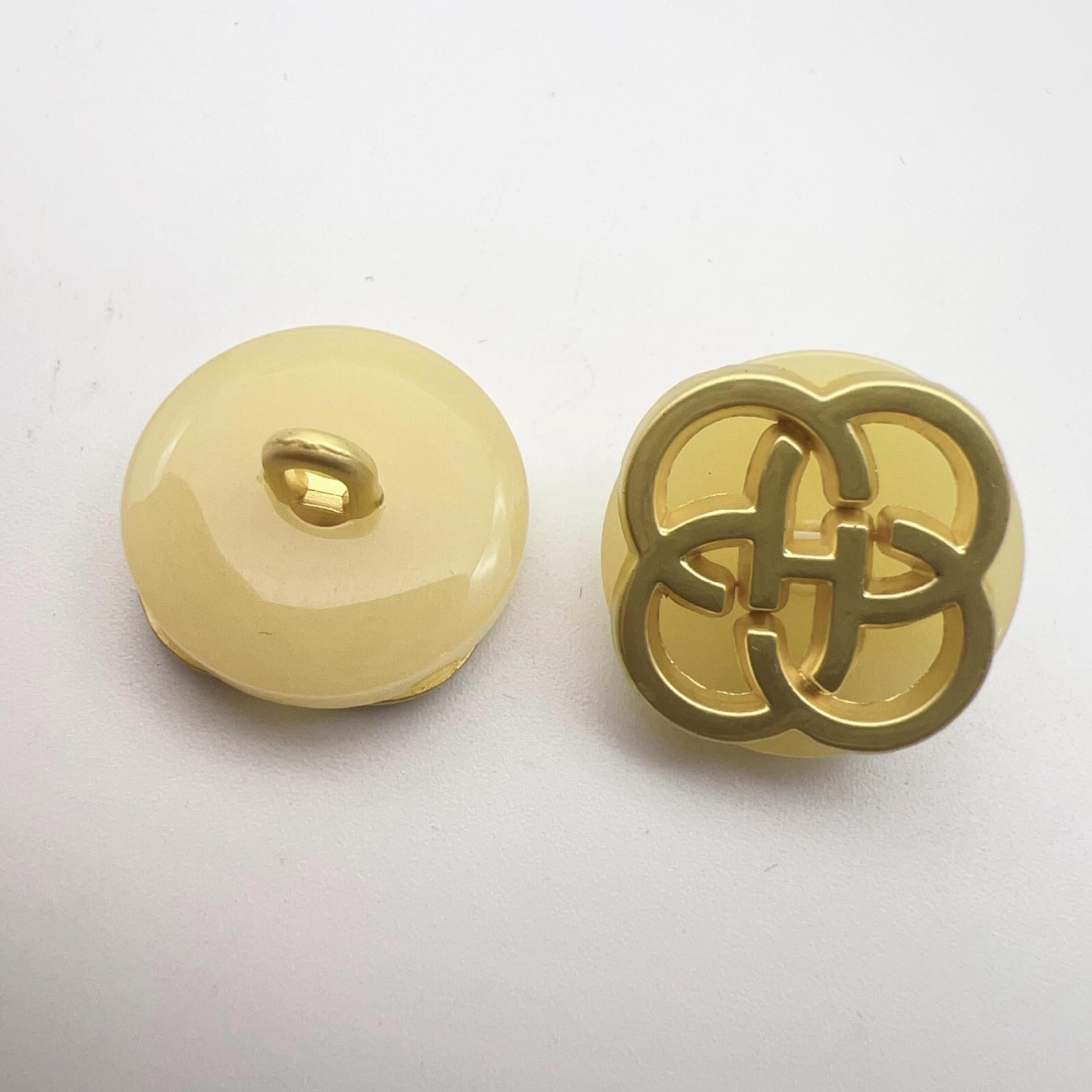 Light yellow resin button with gold-tone four-leaf clover shank