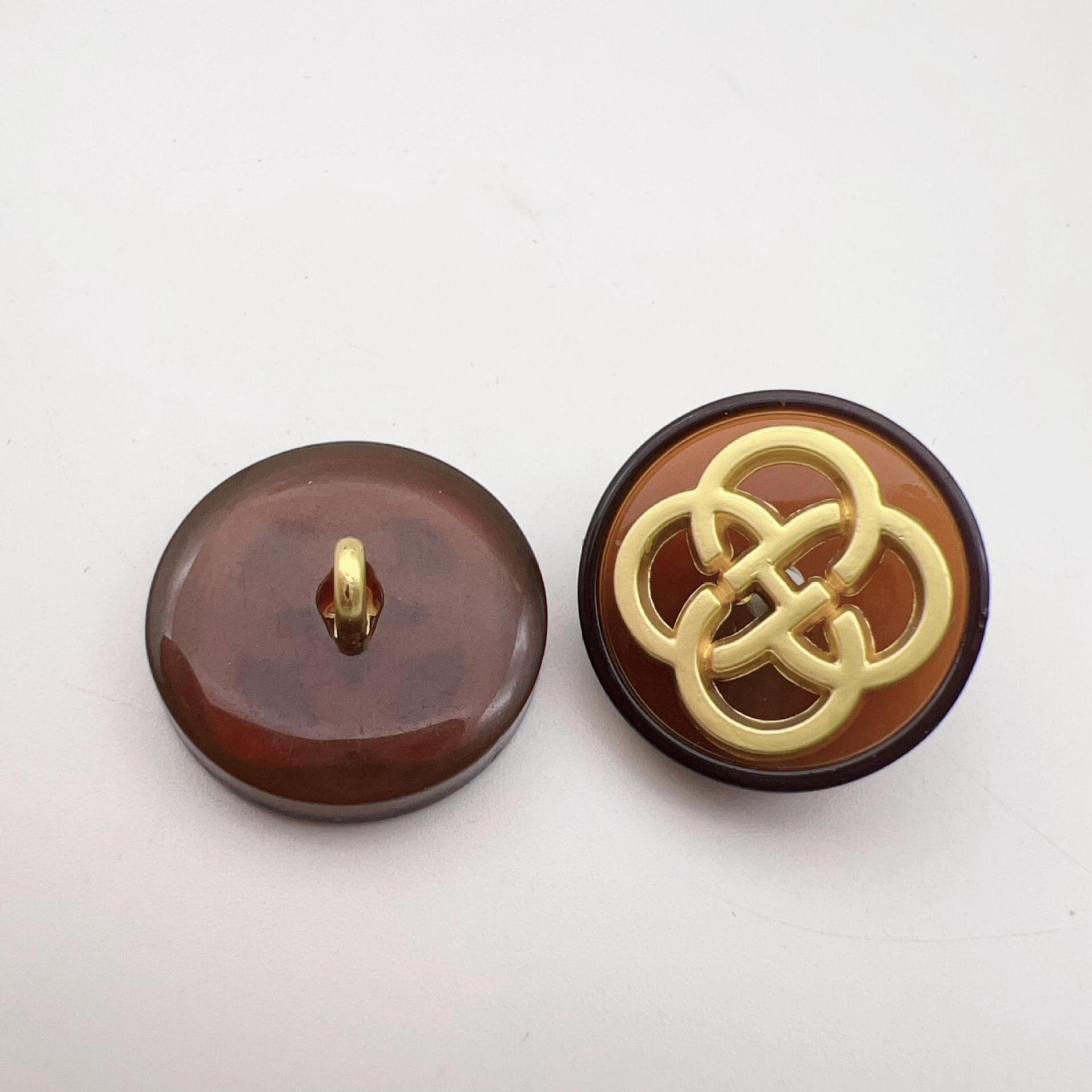 Brown resin button with gold-tone four-leaf clover shank, smooth surface