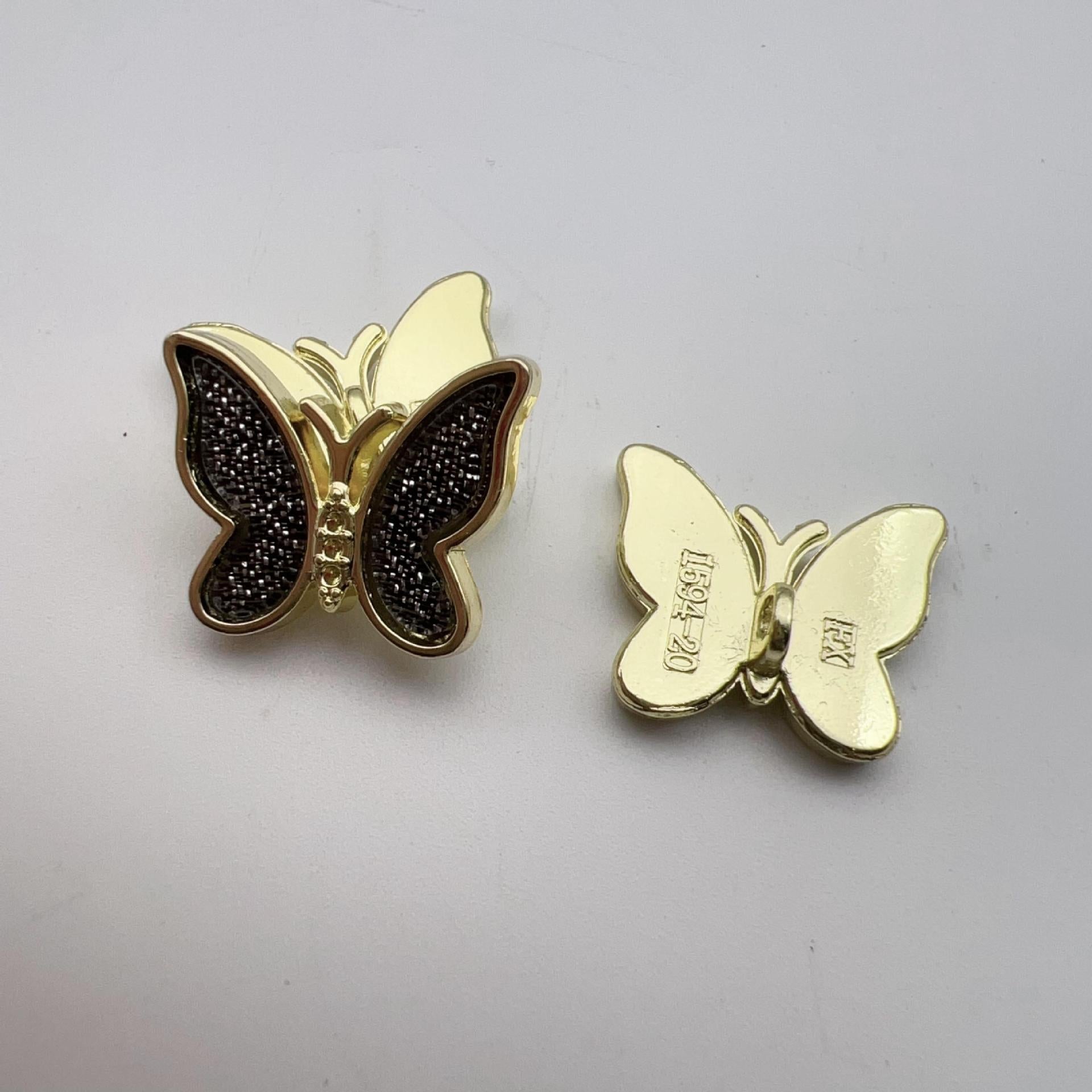 Black butterfly shank button pair with gold-tone edging and glittery center stones