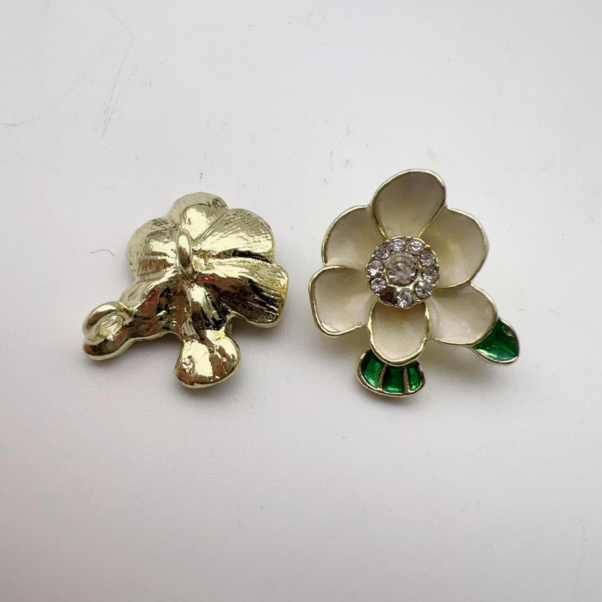 White plum blossom alloy shank buttons with rhinestone centers and green enamel leaves