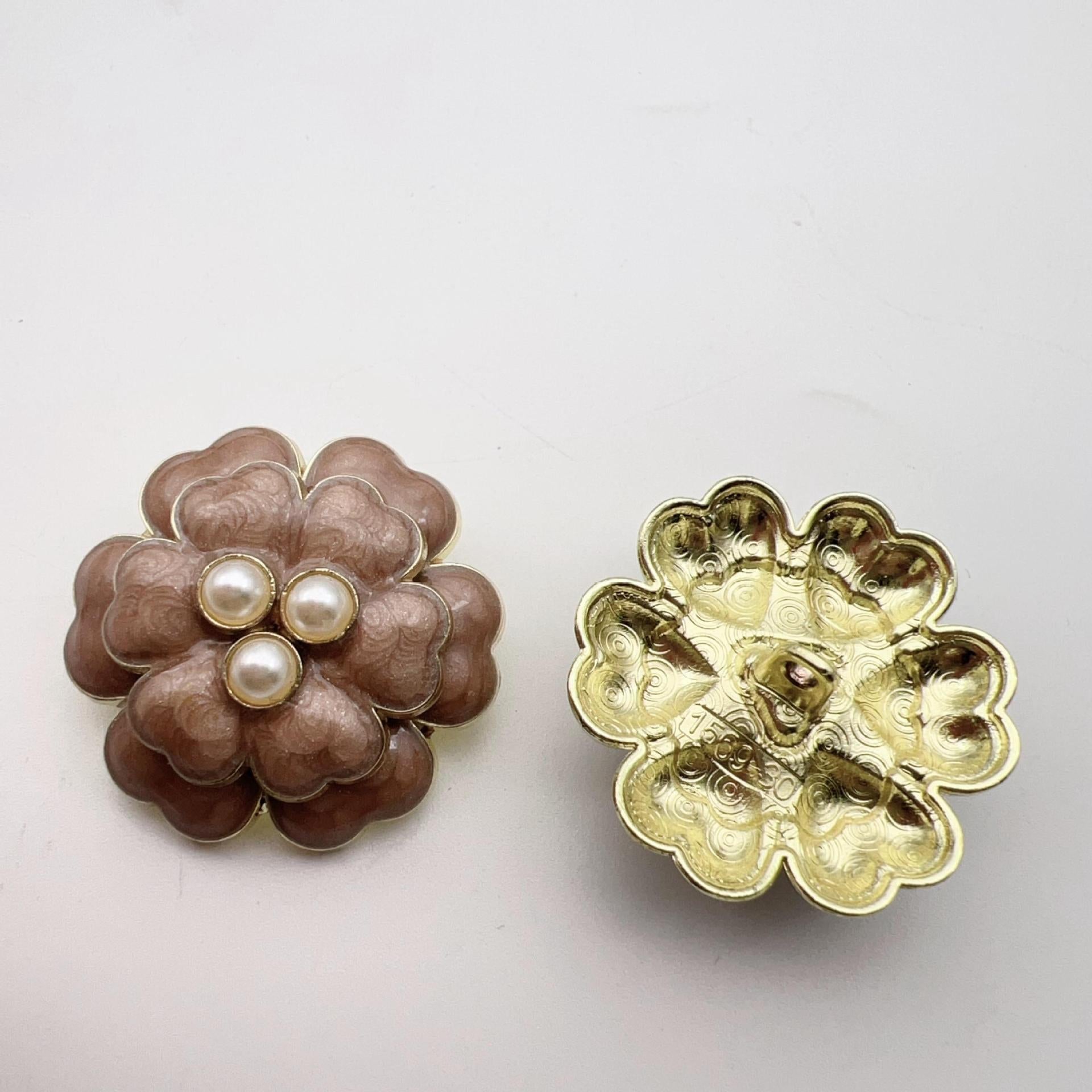 Brown five-petal flower button with three faux pearl centers and gold-toned metal shank back