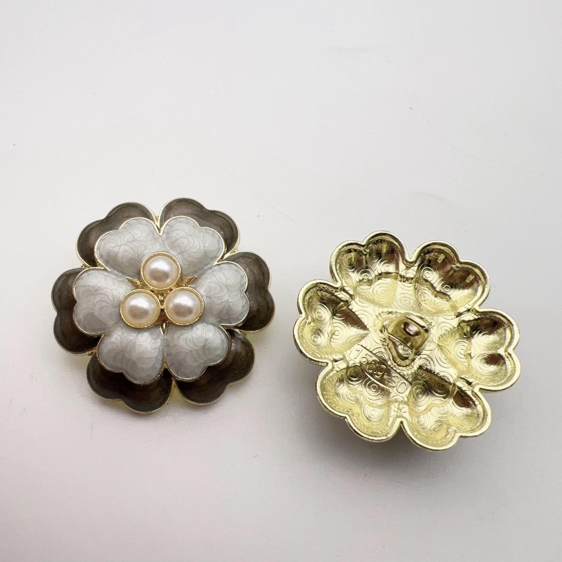 White five-petal flower pearl-look button with three raised pearl centers and gold metal shank back