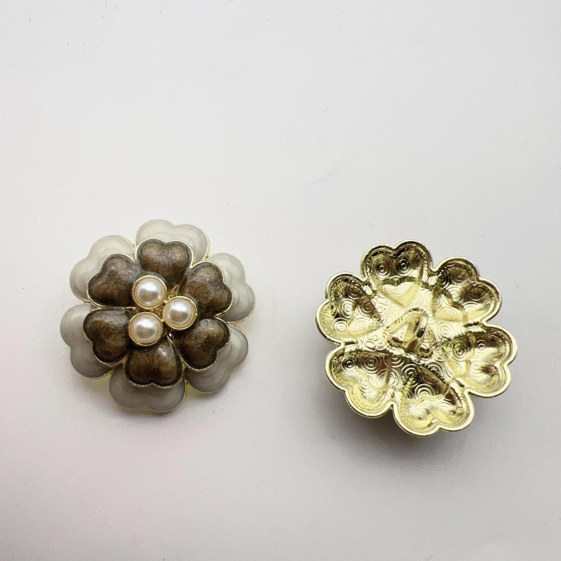 Dark five-petal flower pearl-look button with three raised pearl centers and gold metal shank back