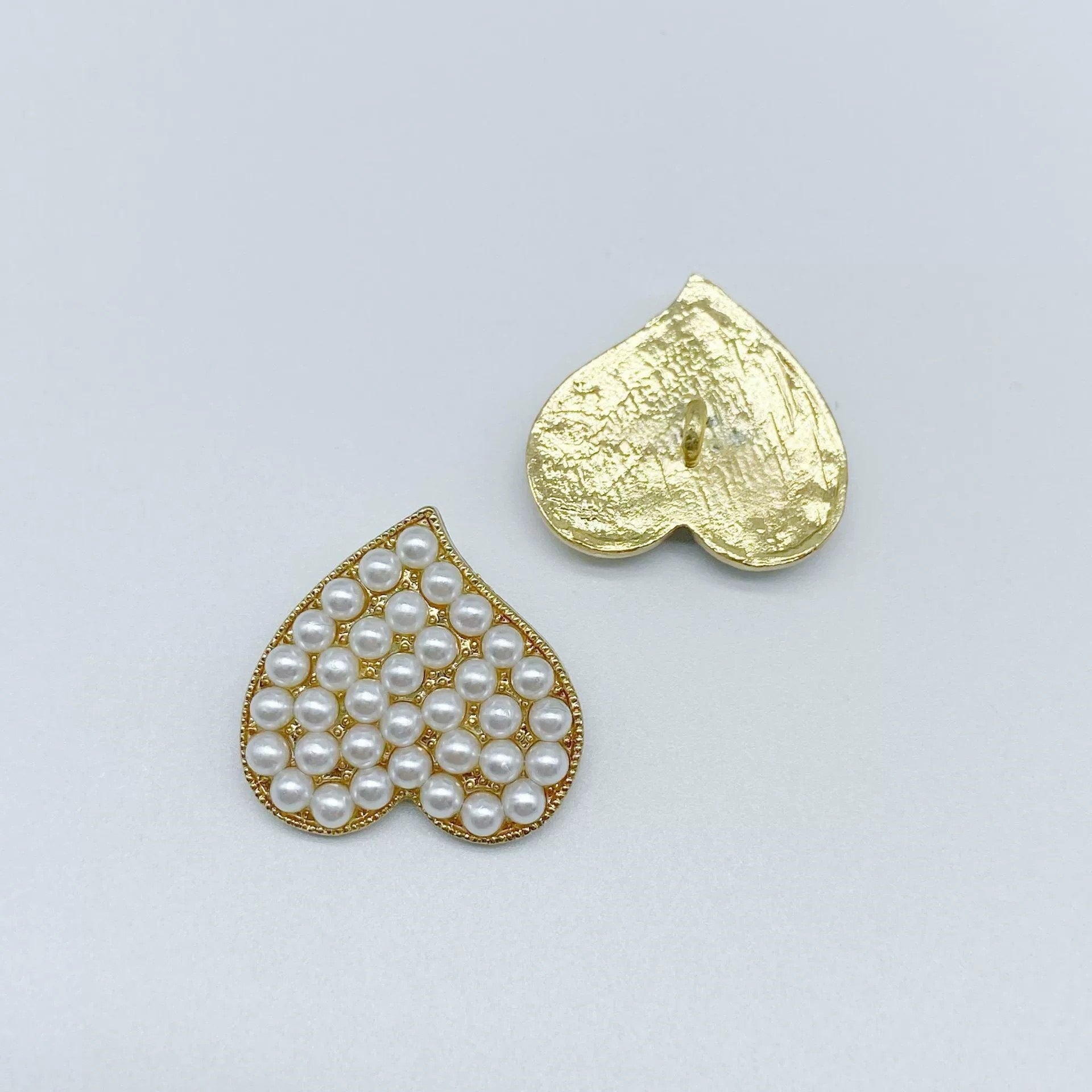 Gold-framed heart coat button with white pearl center and metal shank