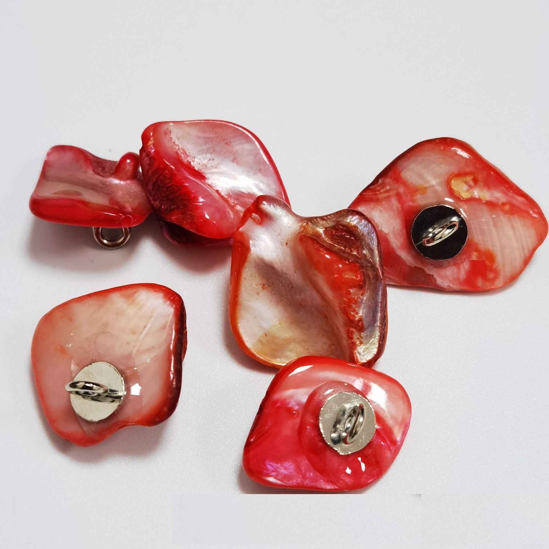 Red/pink irregular shell shank buttons with metal loop shanks, glossy surface.