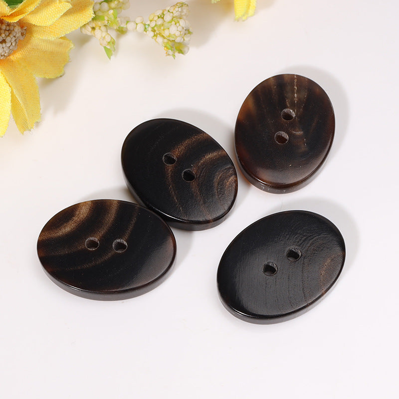 Set of four 23mm oval two-hole horn buttons, dark coffee with visible stitching grain.