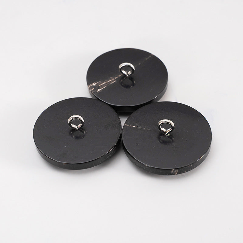 Three 25mm black round buttons, backs with metal shank loops