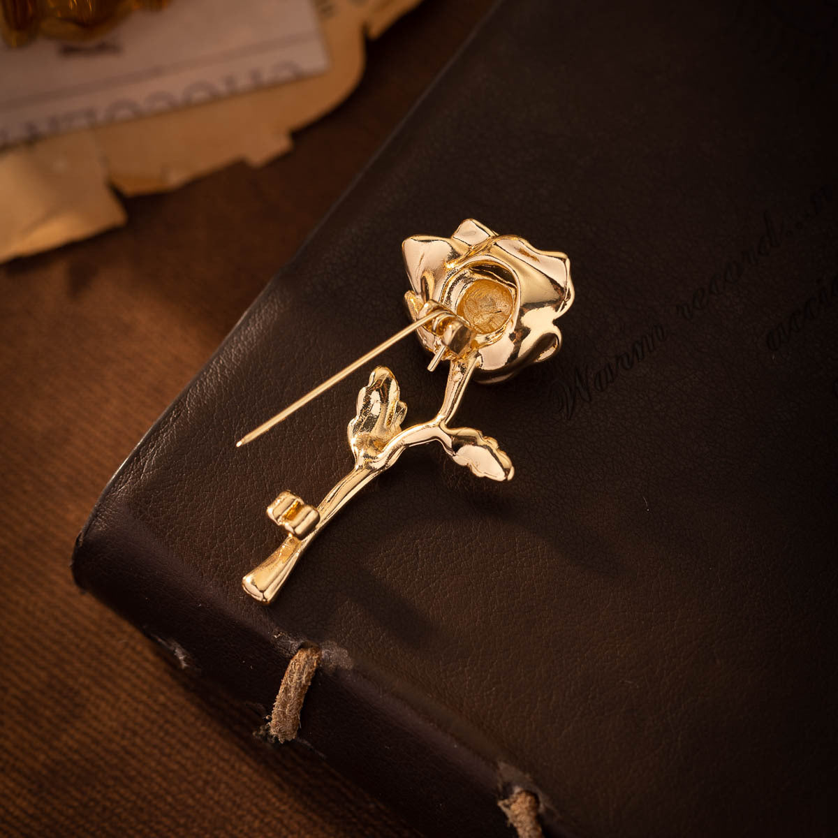 Golden rose lapel pin with detailed rose bloom, leaf, and straight needle post