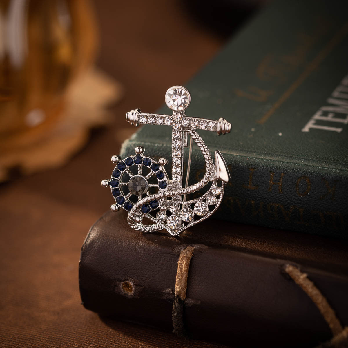 Anker-helm broche met blauw strass, grote donkere kern en witte diamanten, zilverkleurig