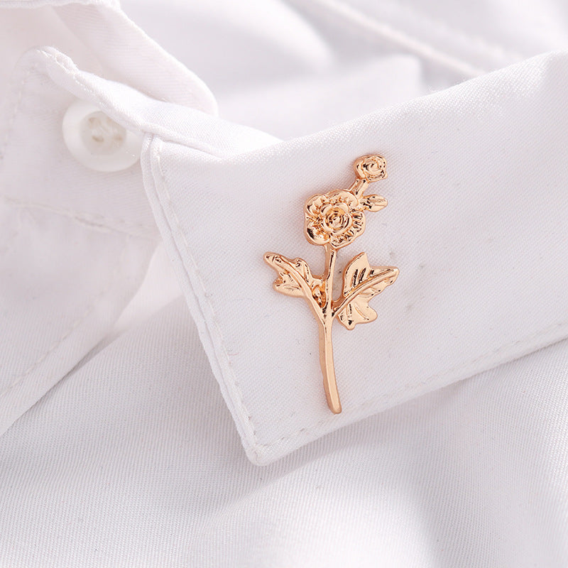 Gold rose branch badge brooch pin on white shirt collar