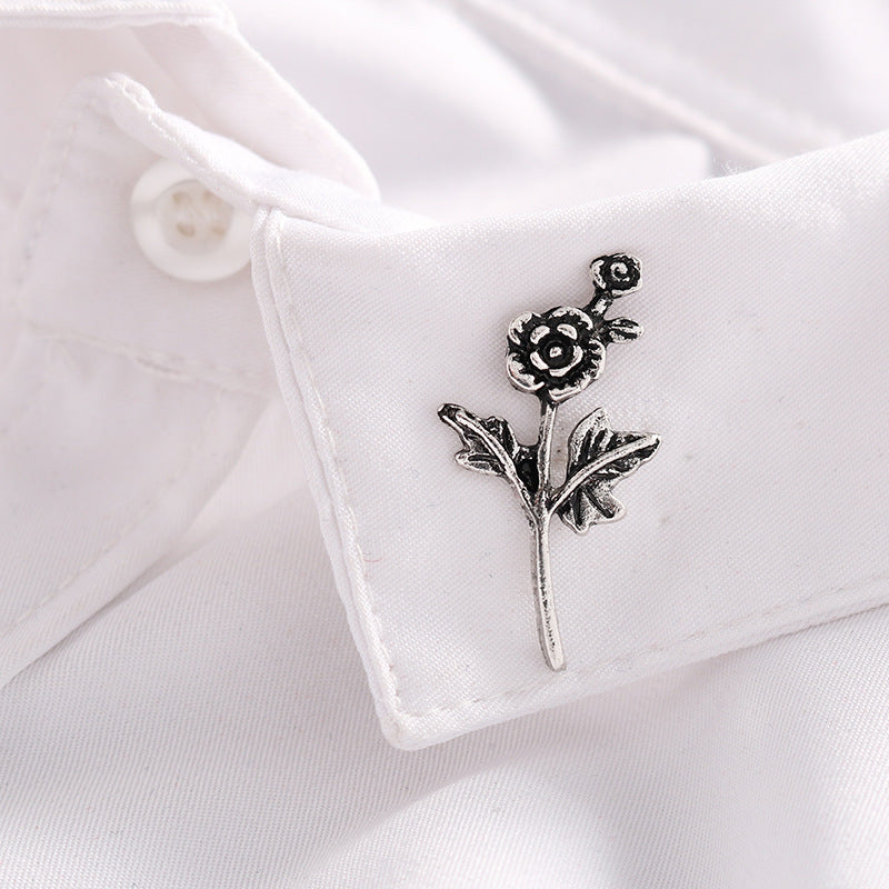 Silver metal rose branch badge brooch pin on white fabric