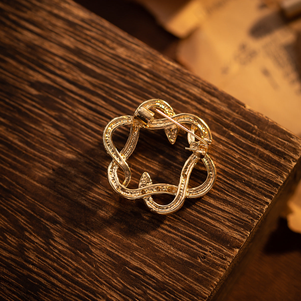 Gold metal brooch with circular openwork, snake motif and small black eye details