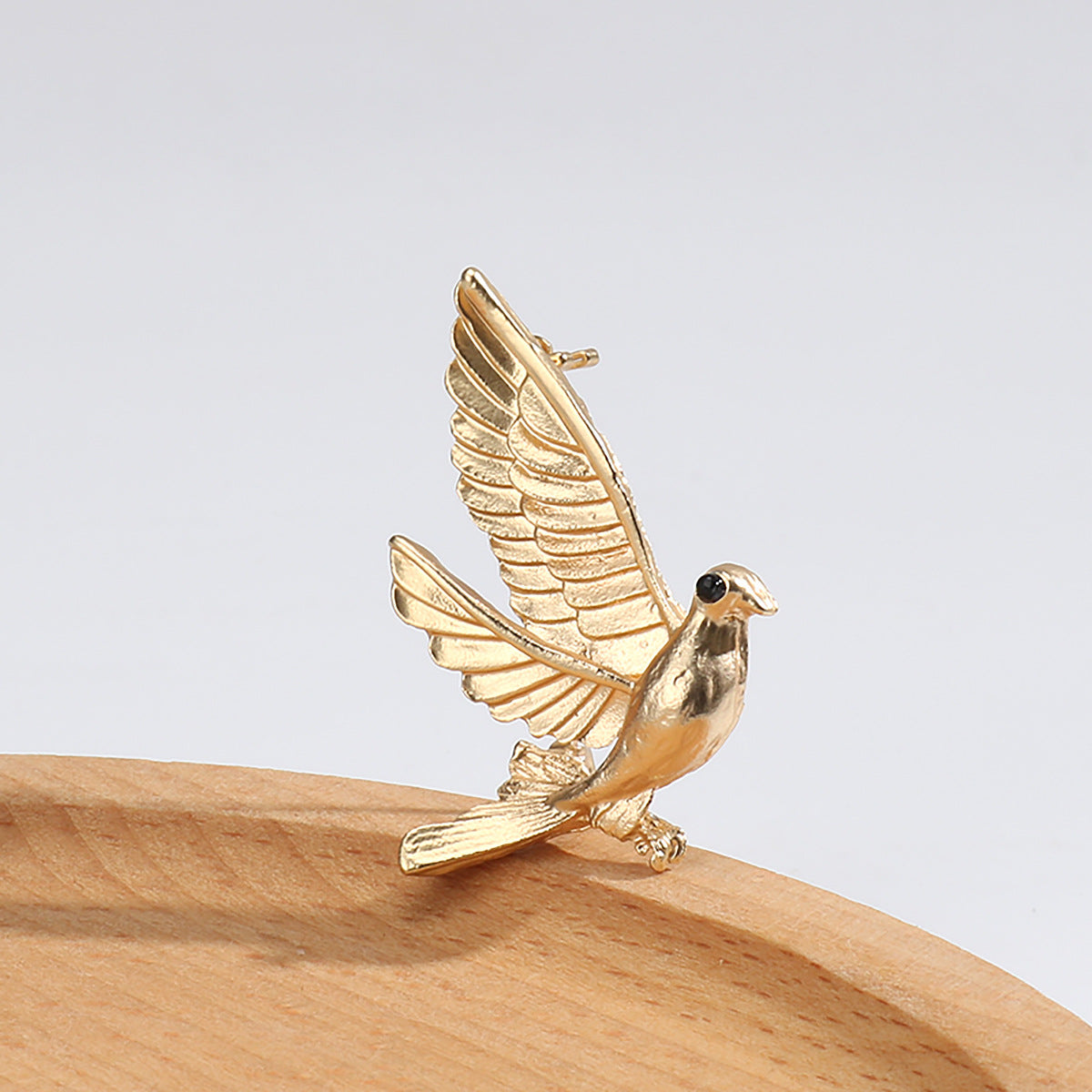 Gold dove metal lapel pin, perched bird with raised wings and black eye