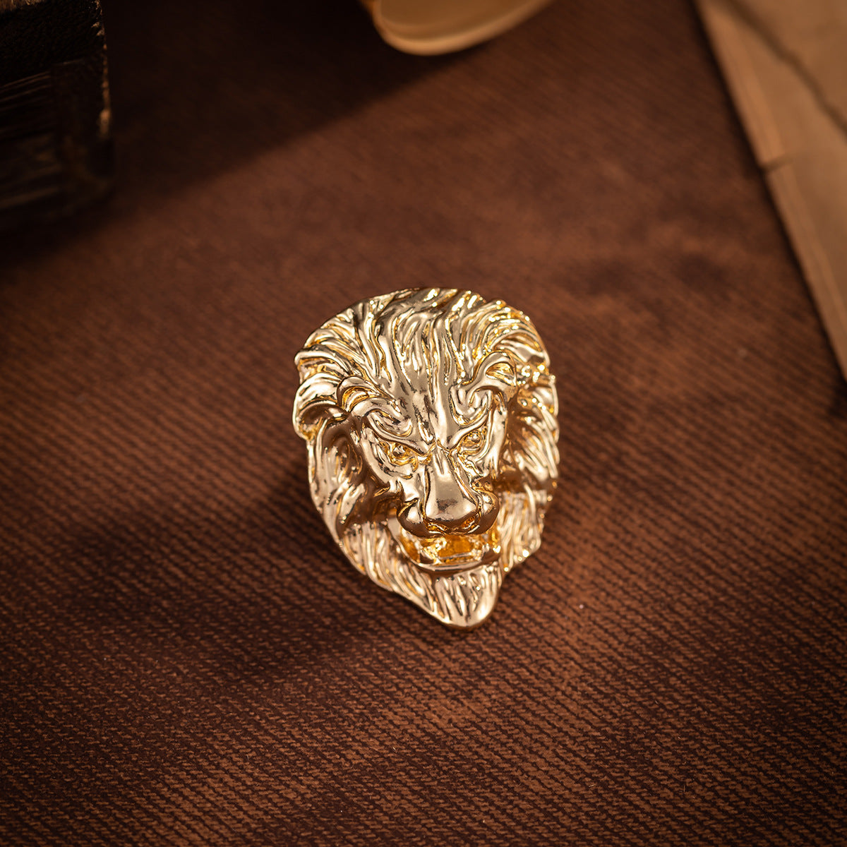 Gold lion head brooch with engraved mane details and open mouth design