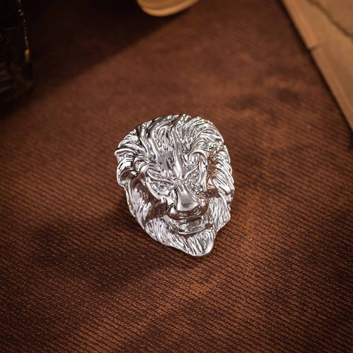 Silver lion head brooch with carved mane texture and metal shine