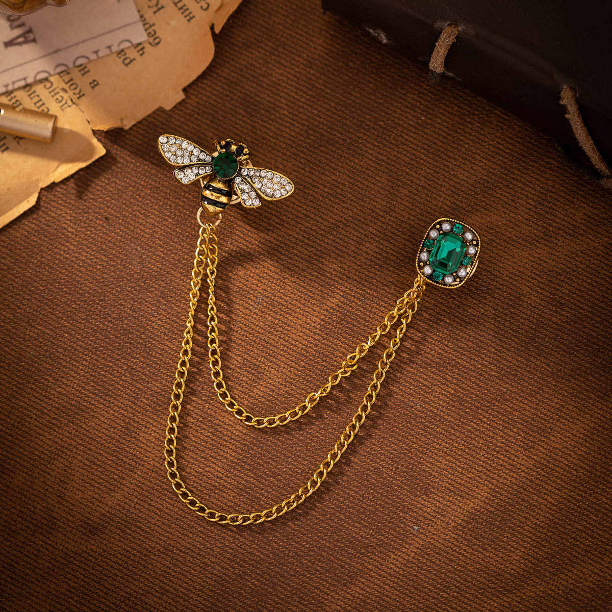 Two bee tassel brooches with green faceted stones, gold-tone chain links, round bezels