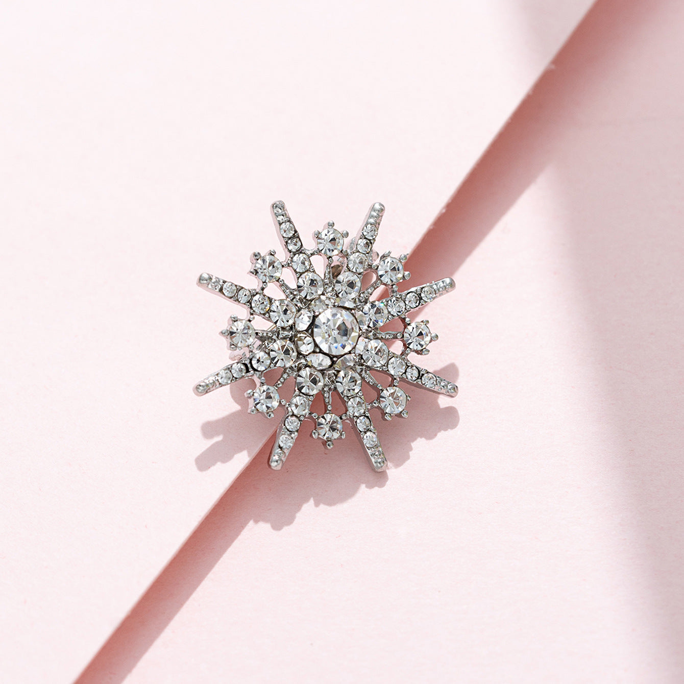 Eight-pointed star diamond brooch, gold-tone frame with clear round crystals and points.