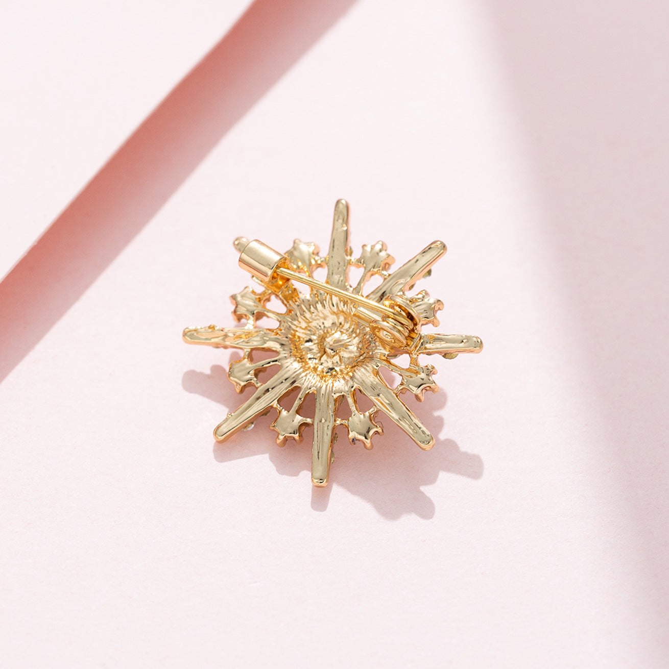 Eight-pointed star diamond brooch, gold-tone metal back shows pin clasp and prongs.