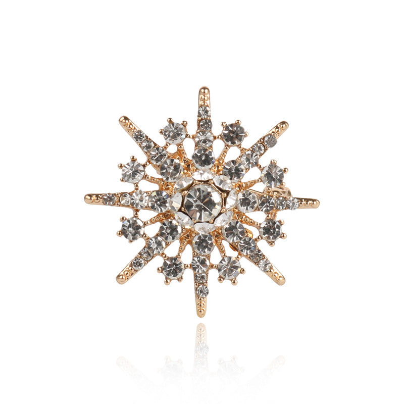 Eight-pointed star diamond brooch with clear crystals on gold-tone metal, front view.