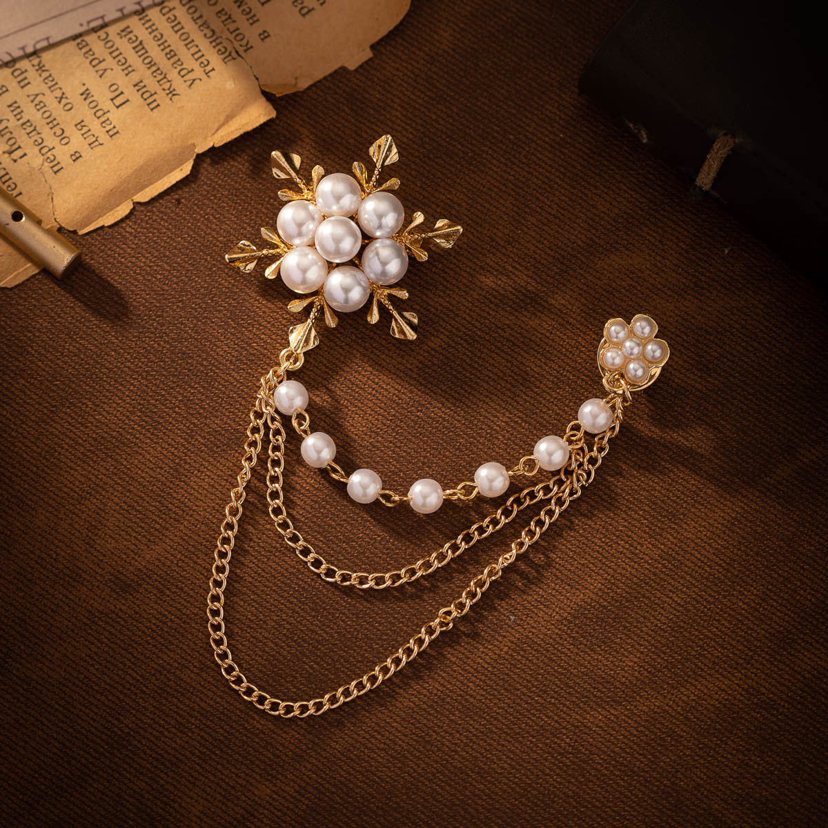 Gold-tone snowflake pearl chain brooch with faux pearl links and starburst center