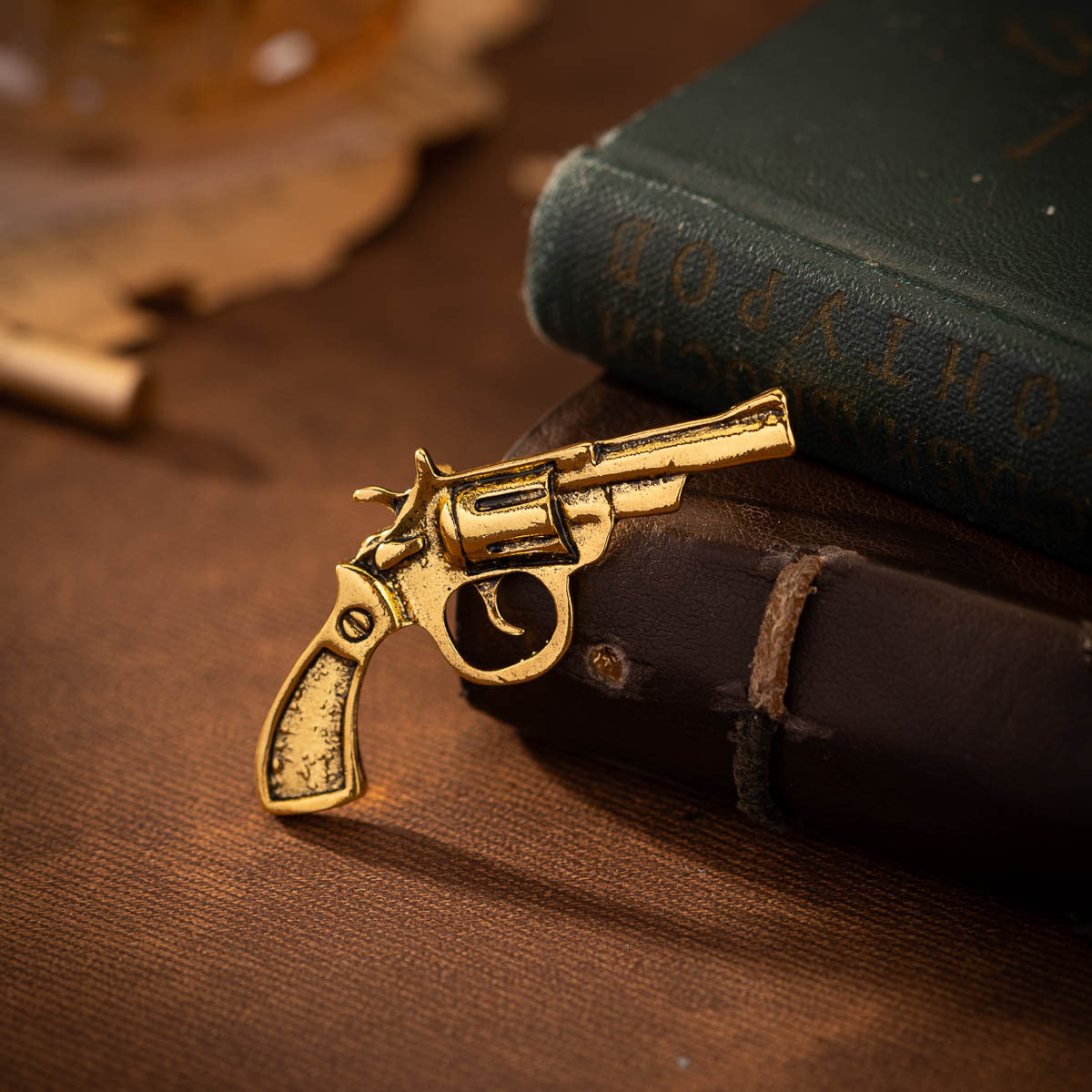 Gold-tone retro revolver brooch with textured grip and barrel detail