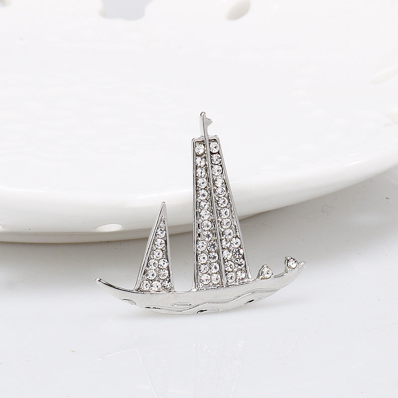Silver-tone sailboat lapel pin brooch, rhinestone sails and small bow details