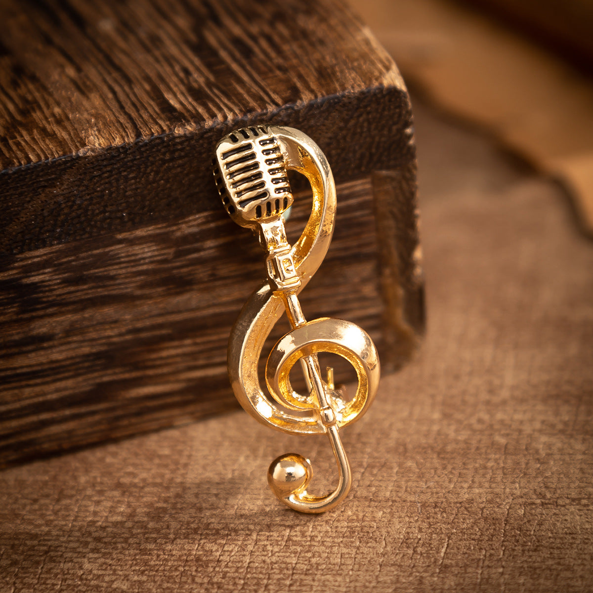 Gold microphone music-note brooch pin, curled hook back, close-up