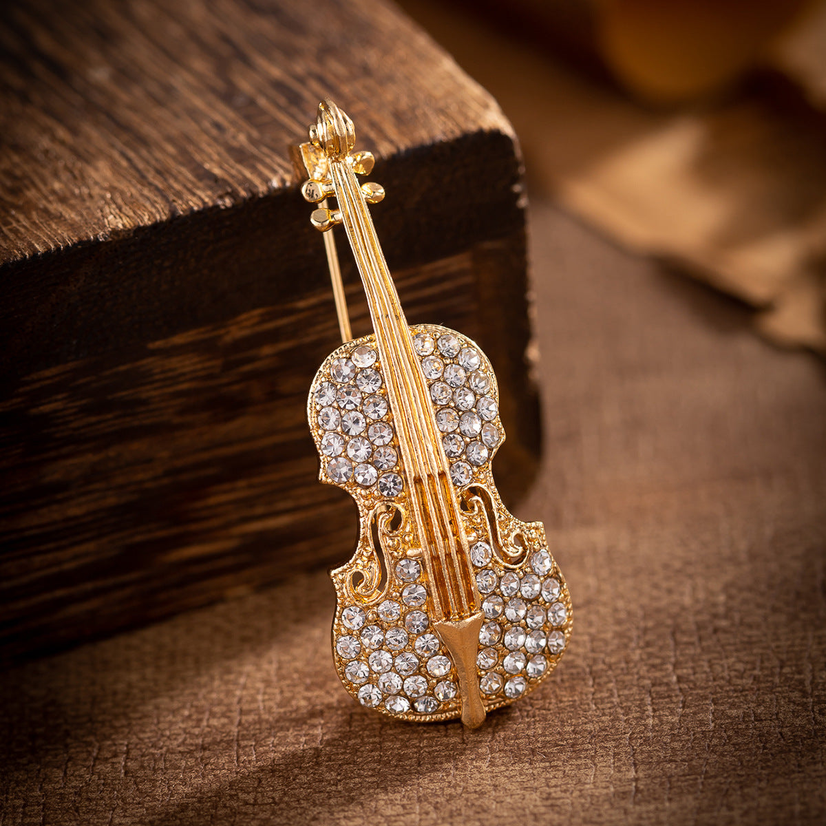 Gold-tone guitar brooch with rhinestone inlaid strings and ornate body