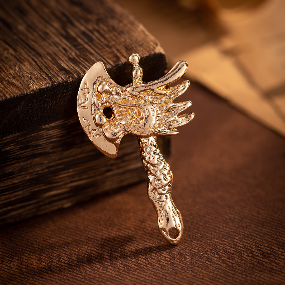 Gold distressed dragon head axe brooch with round eye details and textured handle