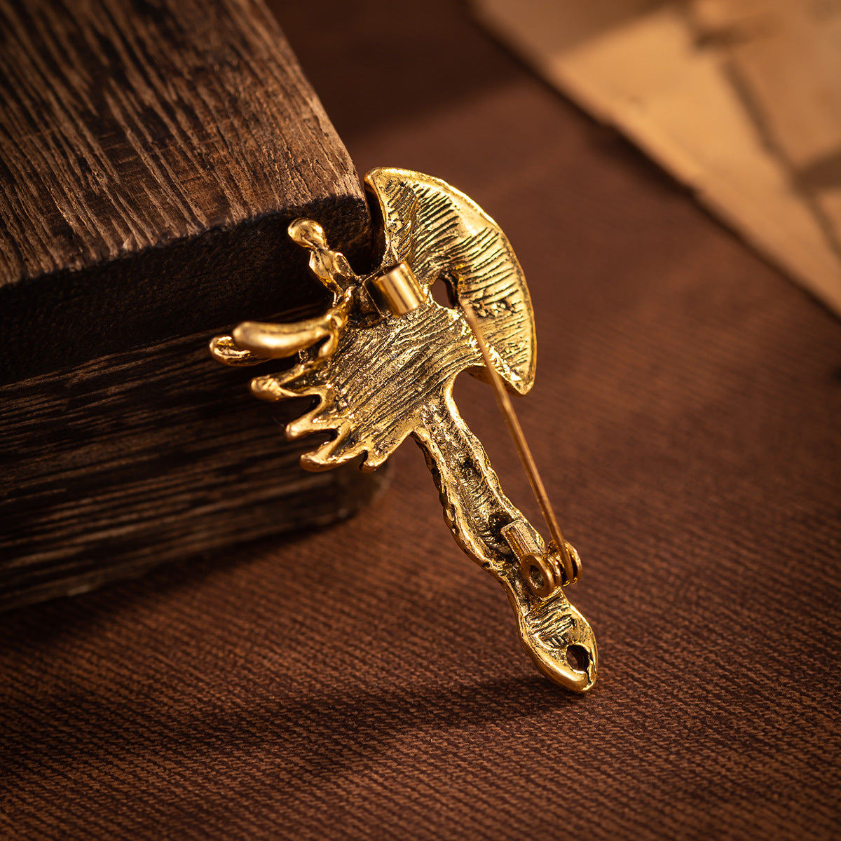 Gold distressed dragon head axe brooch with winged crest and textured handle