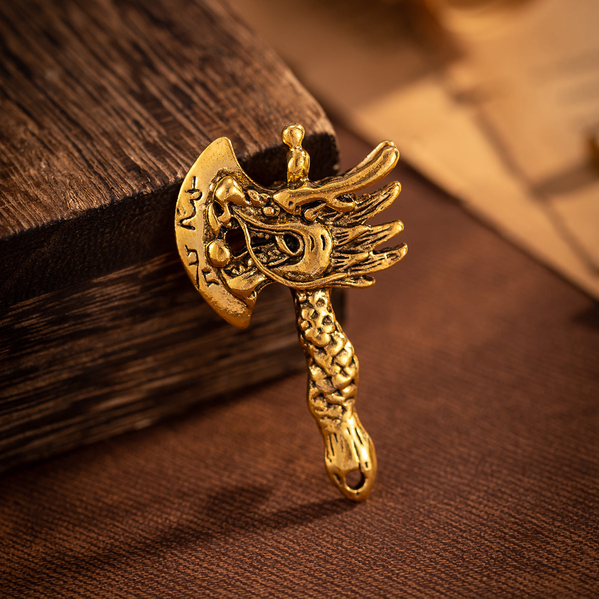Gold dragon head axe brooch close-up with winged design and ornate face