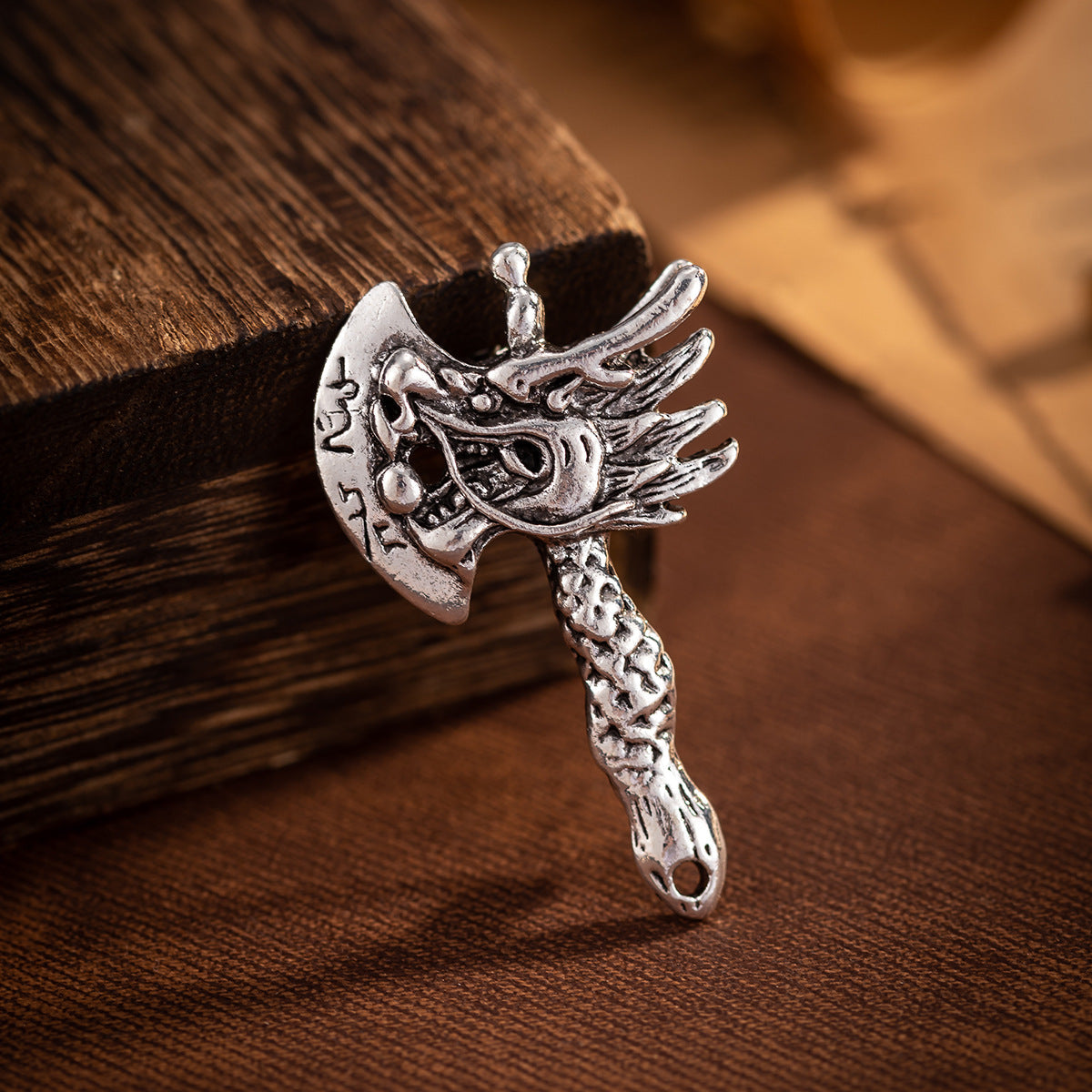 Silver distressed dragon head axe brooch with winged crest and textured handle