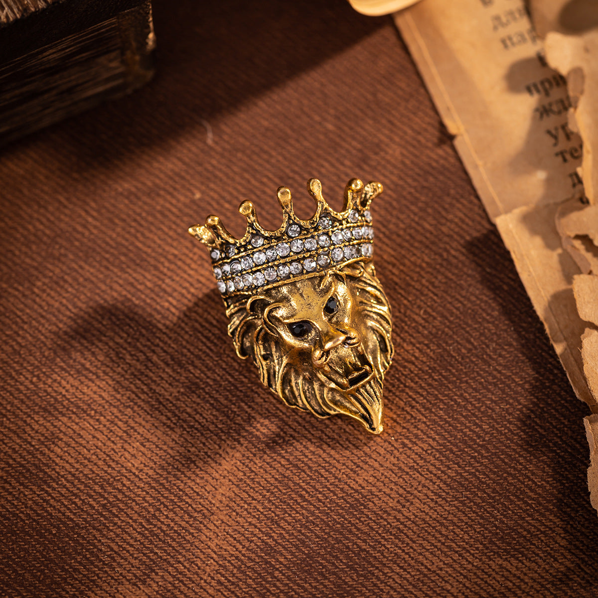 Gold lion head crown pin badge with rhinestone crown trim, front view