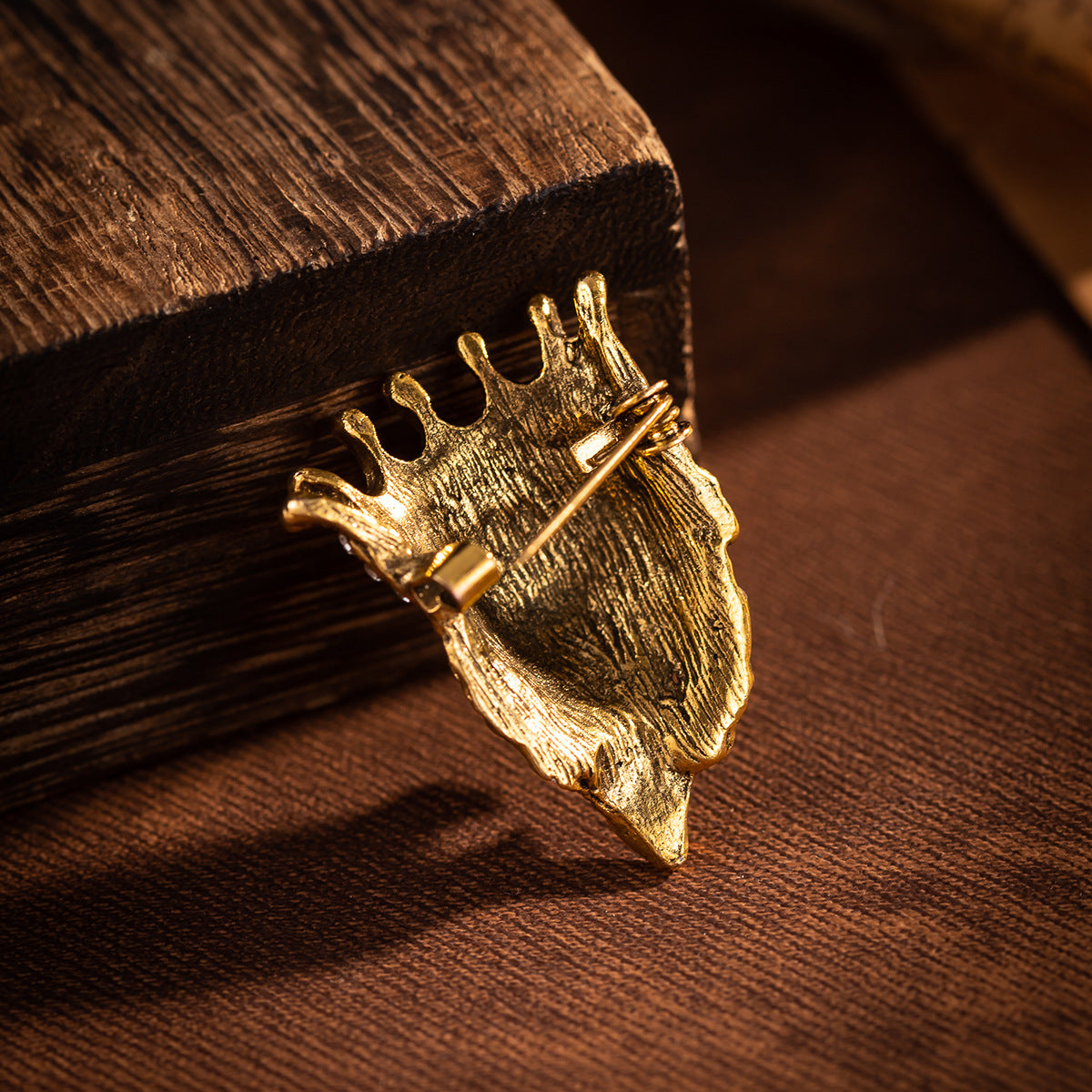 Gold lion head crown pin badge with sparkling rhinestone band, close-up