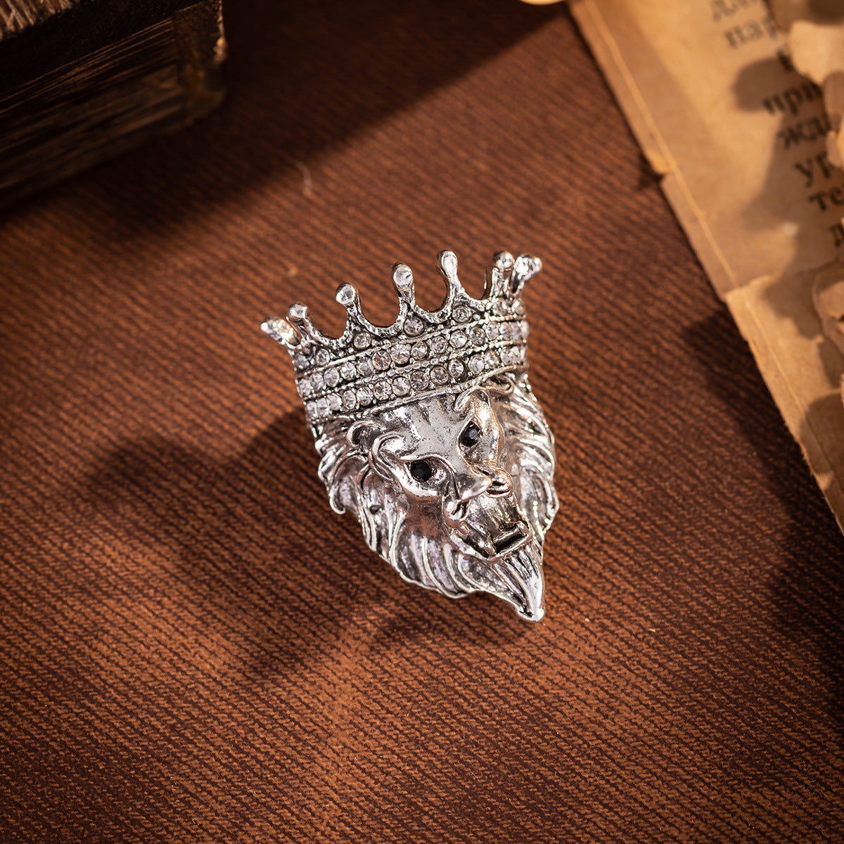 Silver lion head crown pin badge with rhinestone crown and dark eye details
