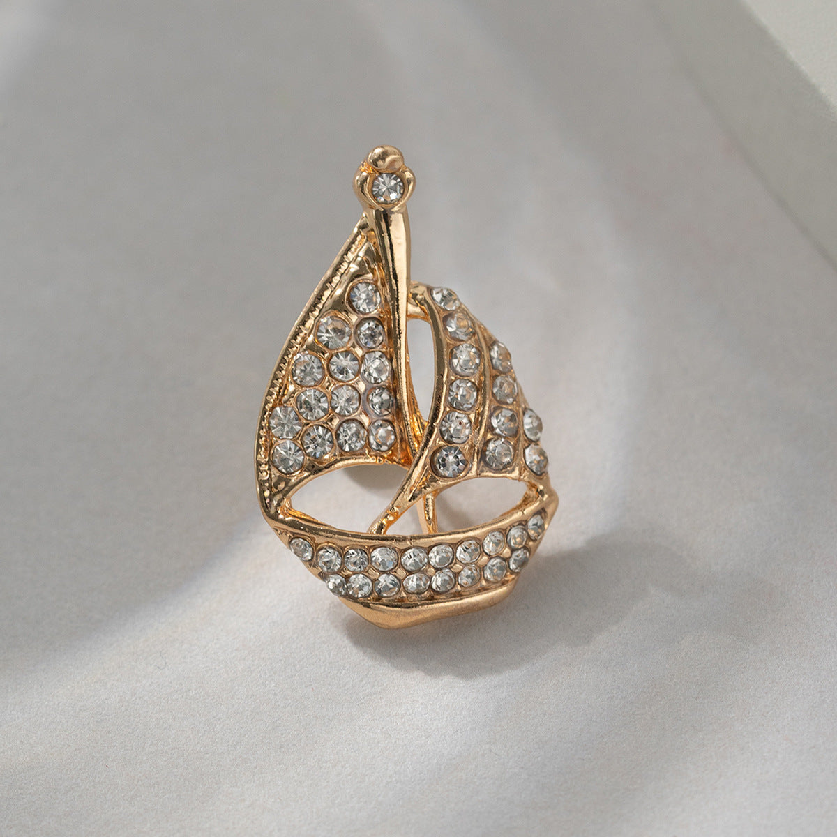 Gold-tone rhinestone sailboat brooch pin with open center and crystal border