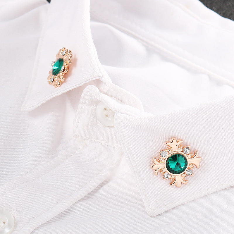 Green cross lapel pin on white shirt collar, rose-gold setting