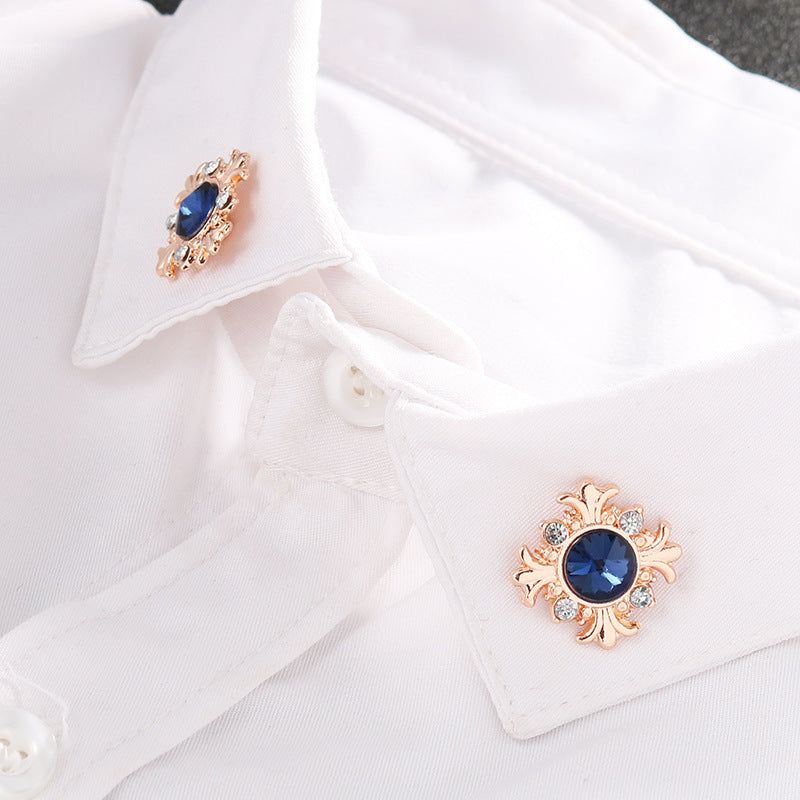 Blue cross lapel pin on white shirt collar, rose-gold setting with clear stones
