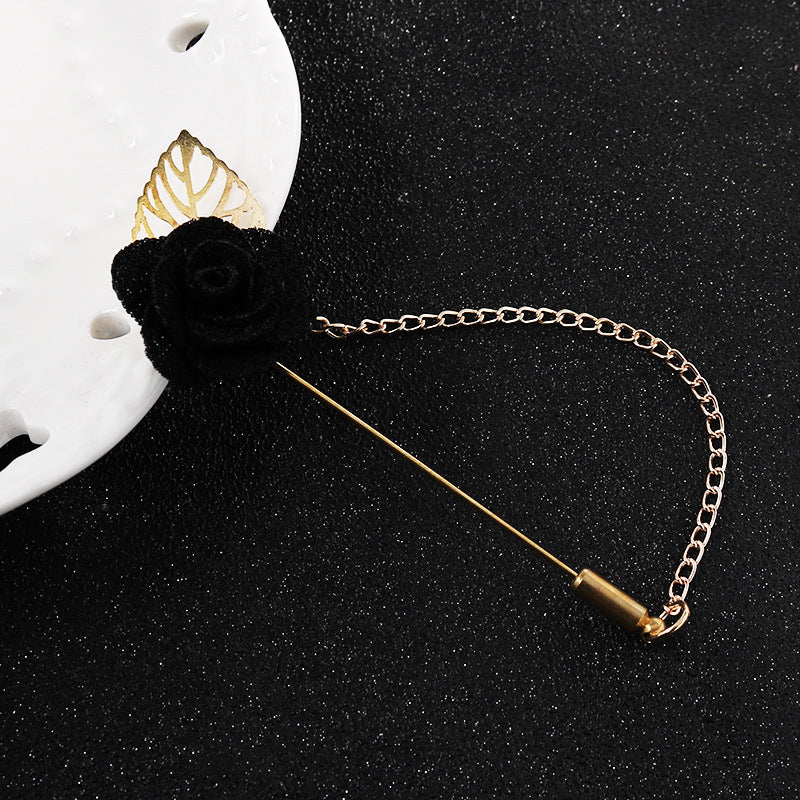 Black flower leaf brooch pin with gold chain and bar closure, close-up