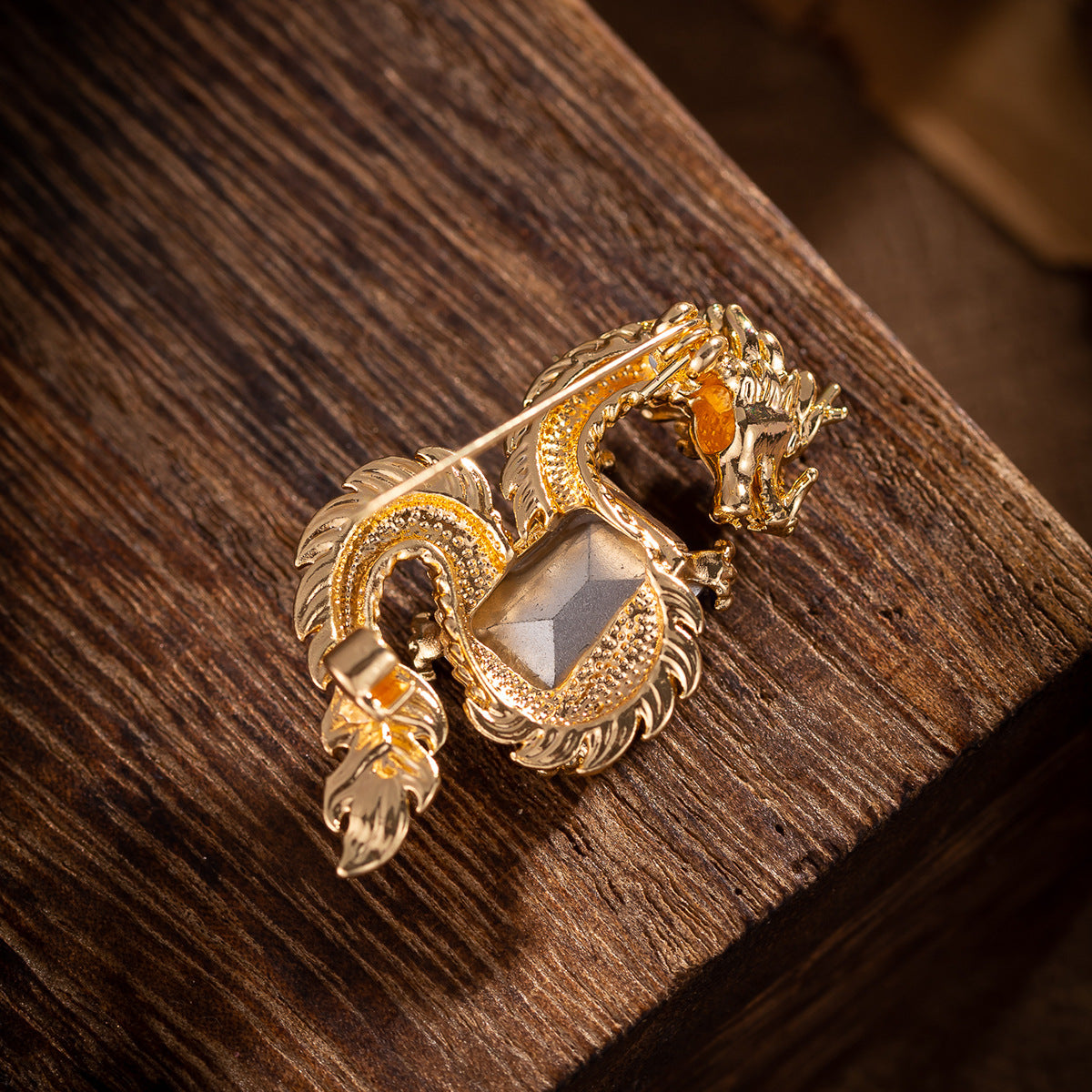Gold-toned dragon brooch with pin clasp back and textured metal details