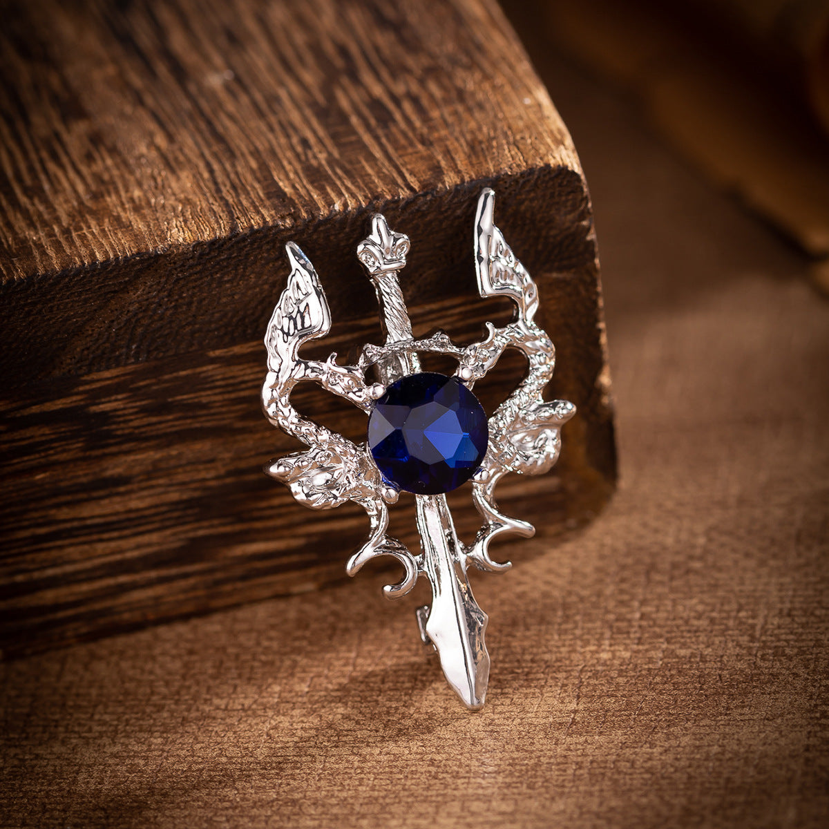Silver double dragon sword brooch close-up with dark blue round gemstone